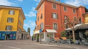 A street with colorful buildings, including a yellow building with a 'bambloo' sign and an orange building with a 'santoni' sign. - Appartamento 30 NODI Torbole 2min walk to Lake, Torbole sul Garda, Italy (Torbole sul Garda)