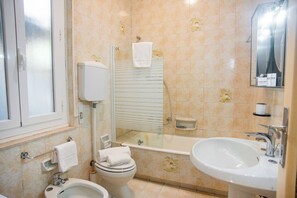 Ein Badezimmer mit Toilette, Bidet, Waschbecken und einer Duschkabine.
