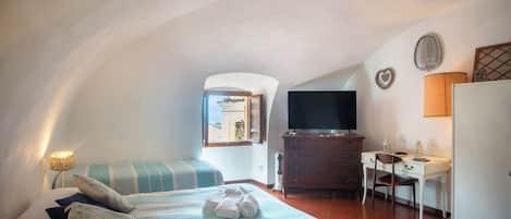 Quarto com cama, escrivaninha, televisão e janela com vista.