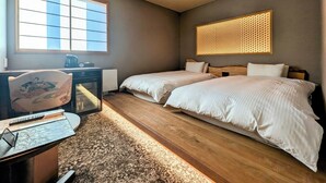 A hotel room with two beds, a desk with a chair, a large window, and a decorative wall panel. - Rashiku Kanazawa (Kanazawa)