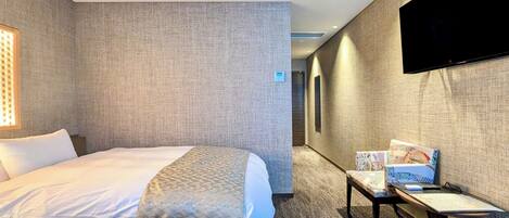 A hotel room with two beds, a TV, a desk, and a carpeted floor.