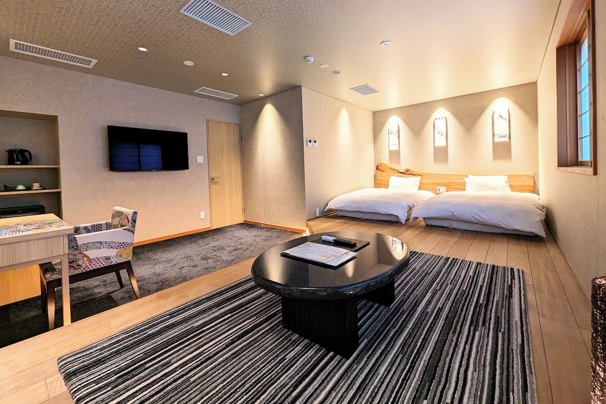 Une chambre d’hôtel avec un lit, un bureau, une chaise, une télévision et une fenêtre.