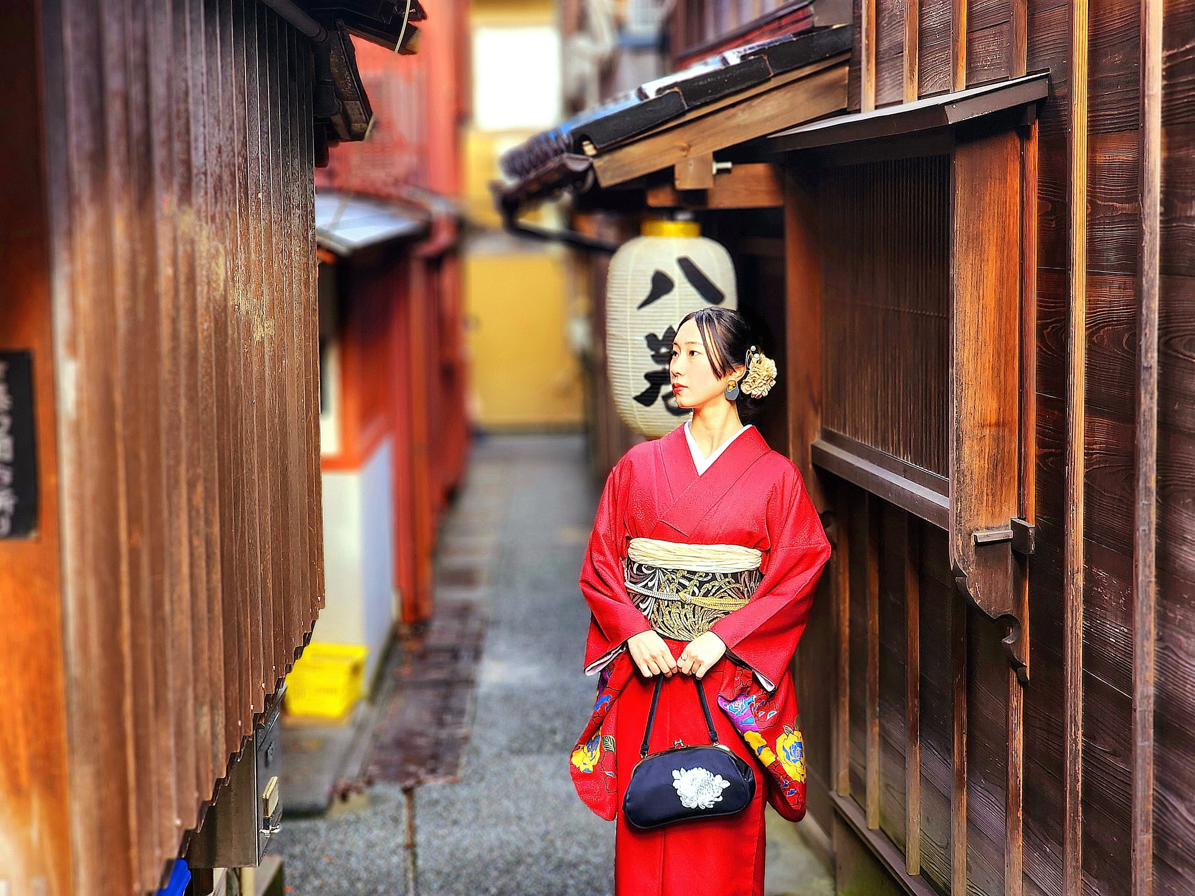 Kapea kujanne, jonka varrella on puisia rakennuksia ja perinteinen japanilainen kyltti.