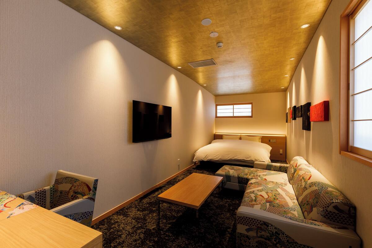 Une chambre d’hôtel équipée d’un lit, d’un canapé, d’une table et d’un téléviseur fixé au mur.