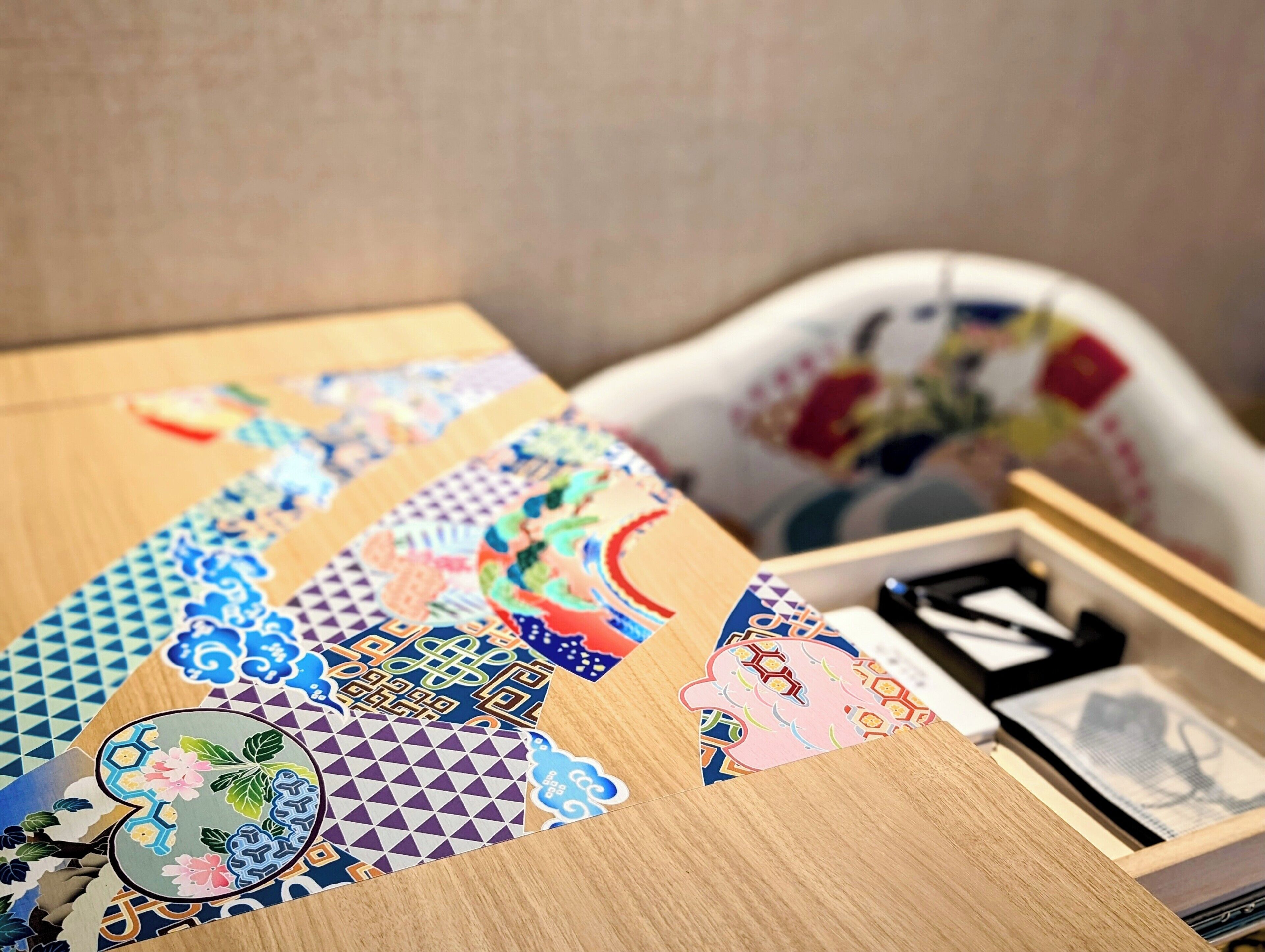 A wooden table with various colorful paper cutouts and a black object on it.