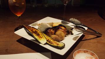 A plate of grilled vegetables and a glass of red wine on a wooden table.