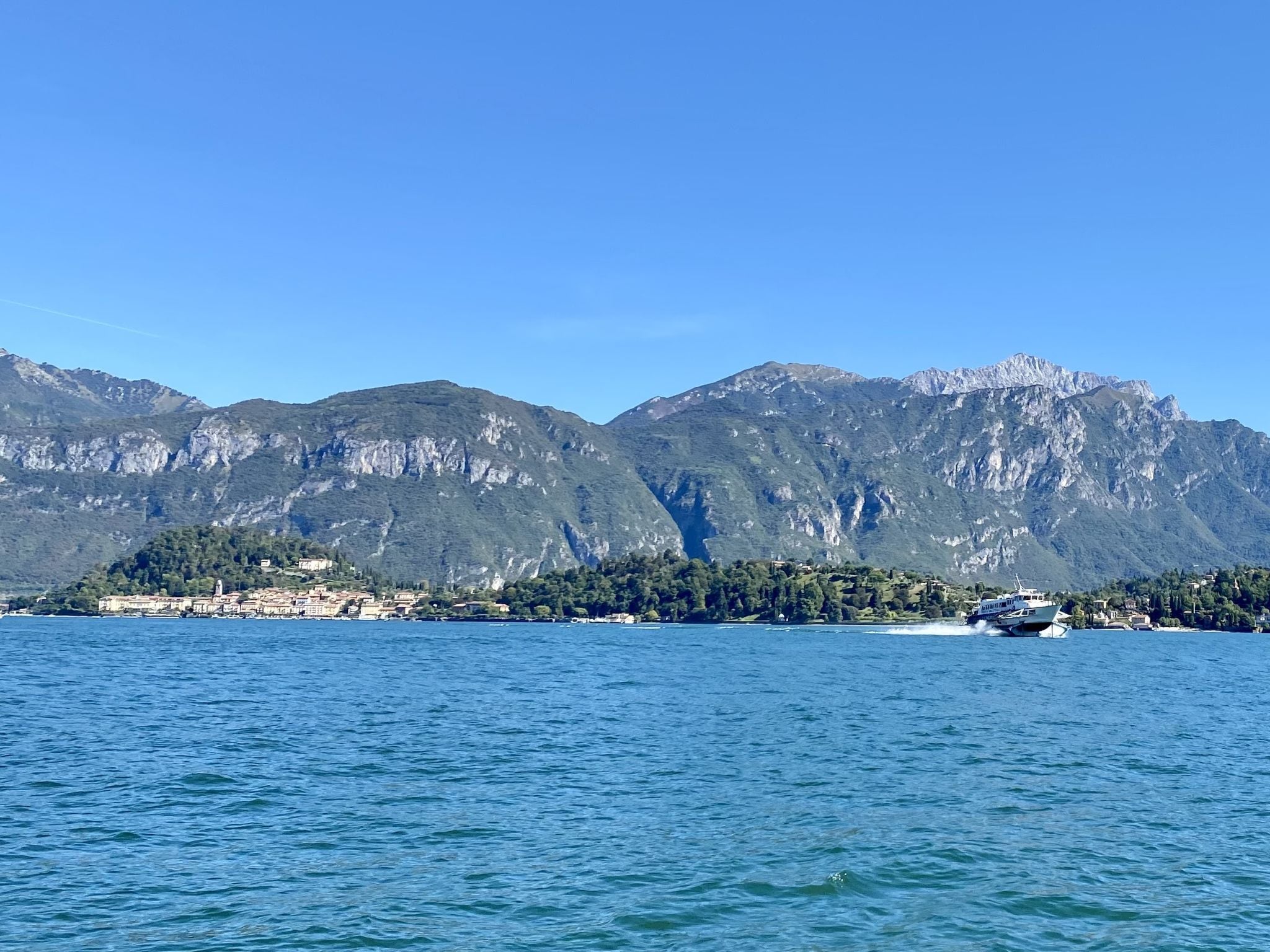 A coastal town with mountains in the background and a boat on the water.