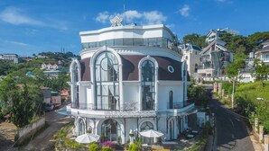 A building with a curved facade, large windows, and a sign reading "PHAM GIAVILLA". - Pham Gia Villa &Hotel (Xuan Huong - Da Lat)