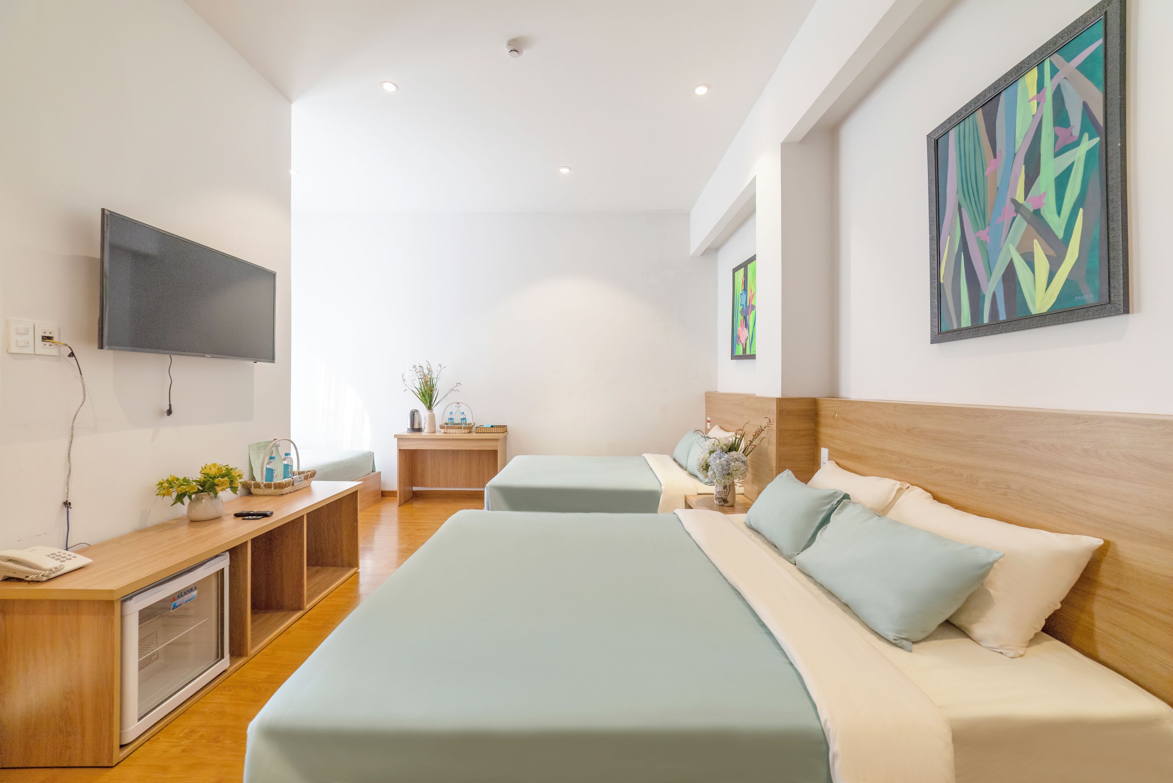 Habitación de hotel con una cama grande, un escritorio con computadora, televisor y obras de arte en las paredes.