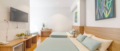Habitación de hotel con una cama grande, un escritorio con computadora, televisor y obras de arte en las paredes.