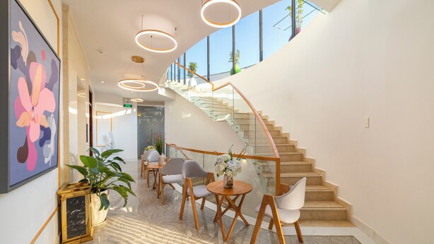 A modern interior with a curved staircase, seating area, and artwork. - Pham Gia Villa &Hotel (Xuan Huong - Da Lat)