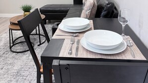 Ein Essbereich mit einem Tisch für vier Personen, einer Couch und zwei gerahmten abstrakten Kunstwerken an der Wand.