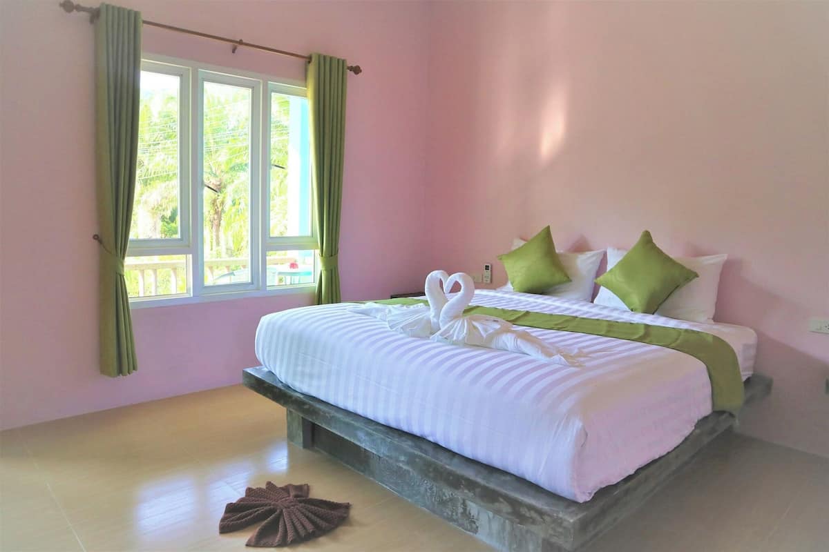 A bedroom with a bed, green curtains, and a window.
