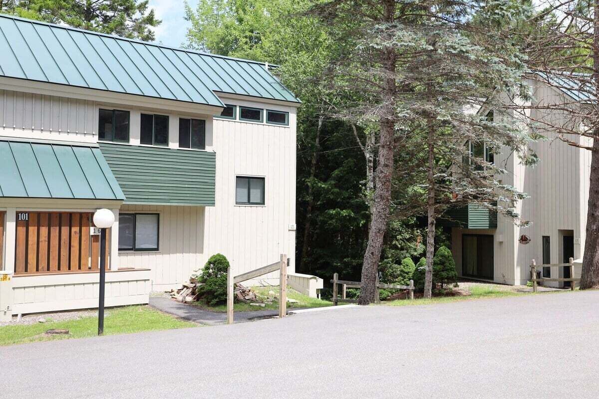A two-story building with a green metal roof, a wooden front door, and a small porch.