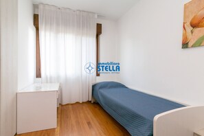 Une petite pièce, bien rangée, avec un lit, une petite table et une fenêtre avec des rideaux.