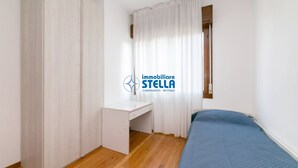 A bedroom with a bed, a desk, and a window with curtains. - Nausicaa Apartment  *few meters from the sea* (Jesolo)