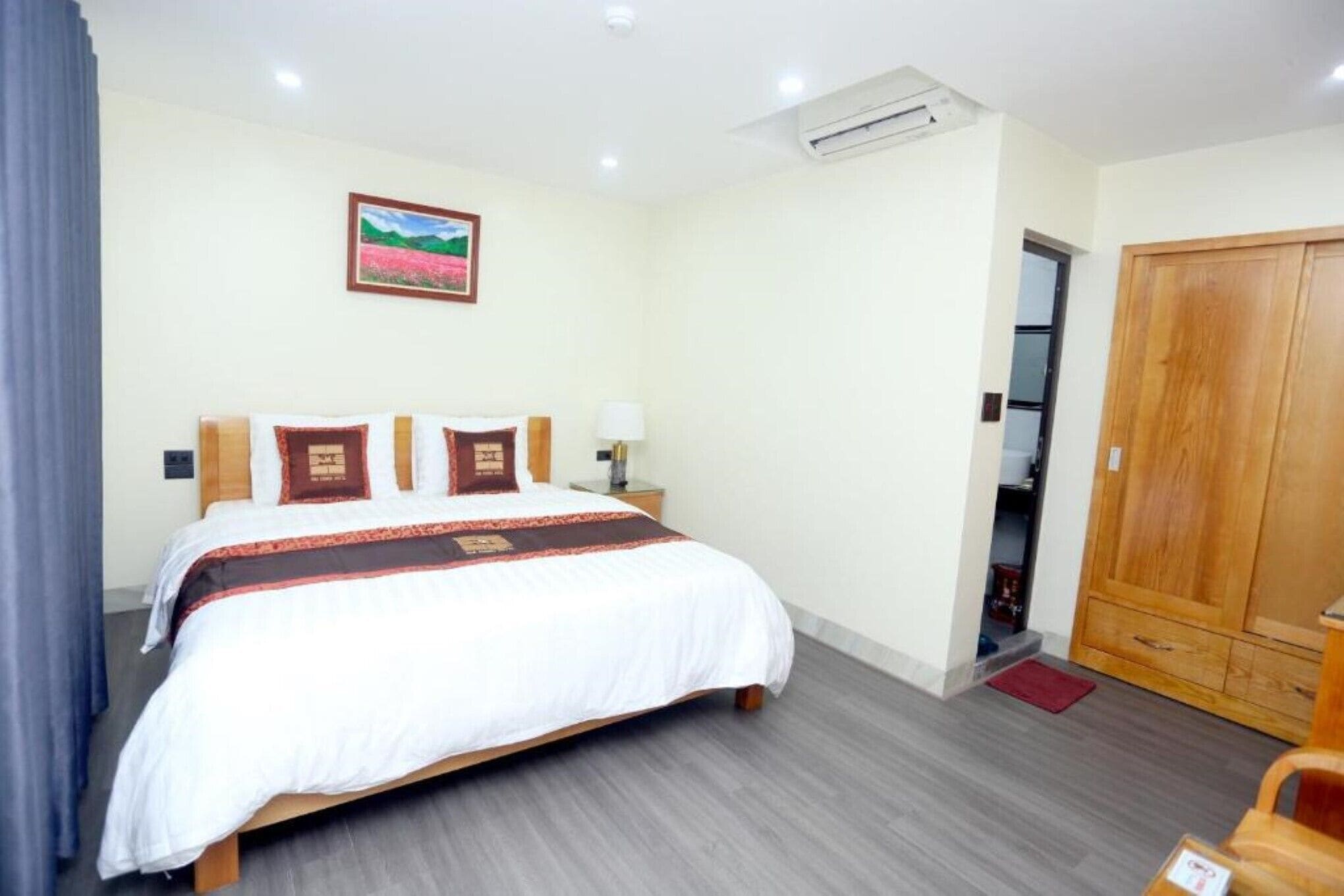 A hotel room with a bed, a wardrobe, a nightstand, and a picture on the wall.