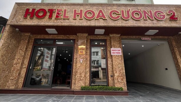 The exterior of Hotel Hoa Cuong 2 with a prominent entrance, air conditioning units, and a tiled pavement. - Hoa Cương Hotel 2 (Ha Giang 1)