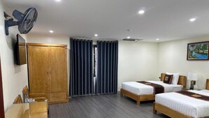 A hotel room with two beds, a desk, a wardrobe, a TV, and a painting on the wall. - Hoa Cương Hotel 2 (Ha Giang 1)