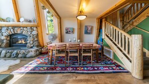 A cozy interior with a stone fireplace, wooden dining table, and chairs, surrounded by a colorful rug. - 4BD w/Lake Views - Near Beach and Slopes (Tahoe City)
