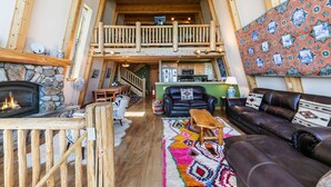 A cozy living room with a fireplace, a leather sofa, a colorful rug, and a balcony with wooden railings. - 4BD w/Lake Views - Near Beach and Slopes (Tahoe City)
