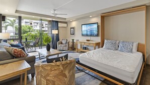 A modern hotel room with a large bed, a desk, a TV, and a balcony with a view of the city. - Walk to Beach | Pools, Pickleball, Kihei (Kihei)
