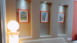 Un salon moderne avec un canapé beige, une table ronde et trois tableaux encadrés accrochés au mur.