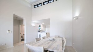 A modern dining area with a large table, white chairs, and a bowl on the table.