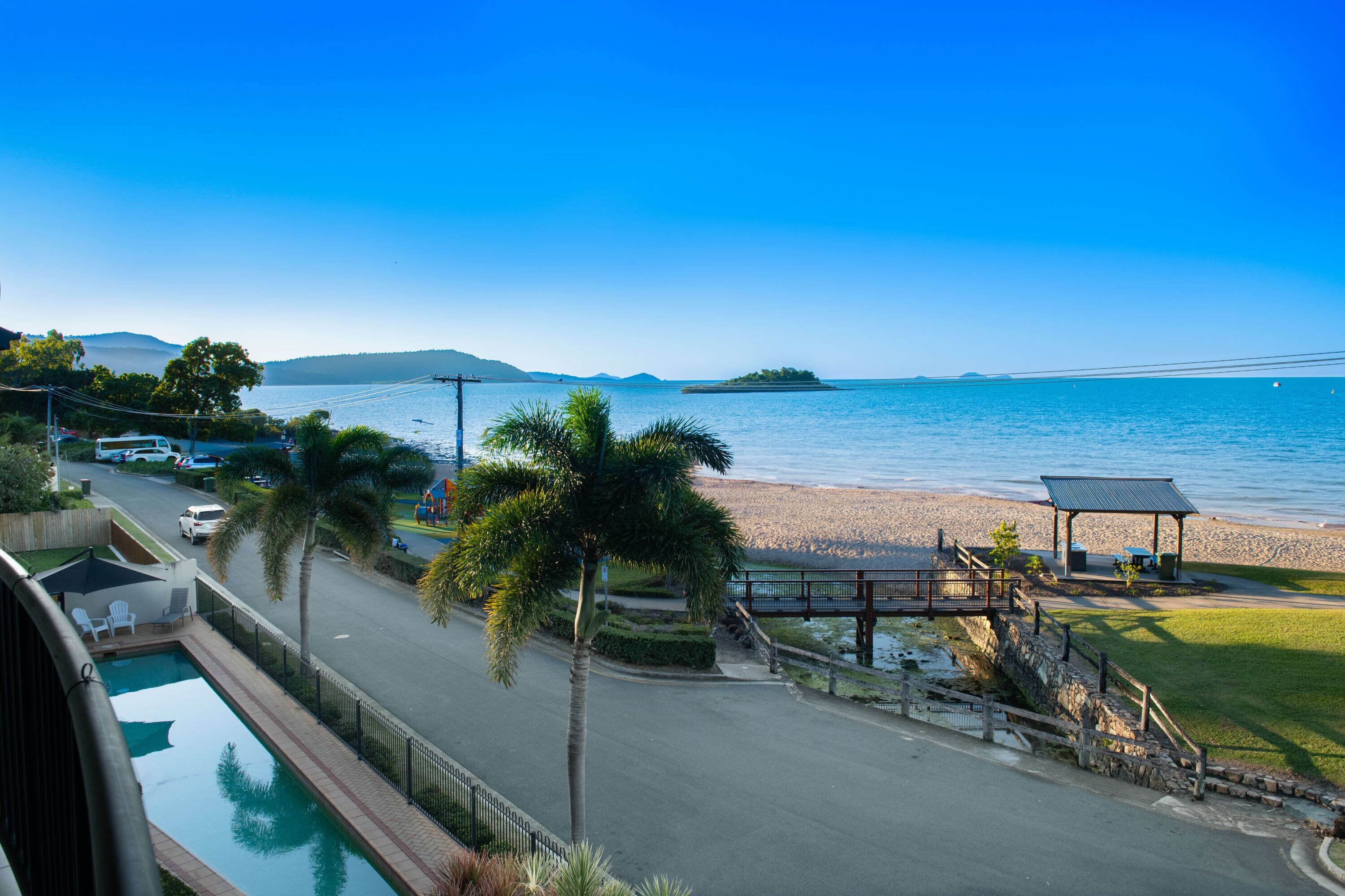 A view of a beach with a pool, palm trees, and a gazebo.