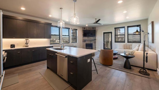 A modern kitchen with dark cabinets, a central island, and pendant lighting. - Retreat at Jordanelle | Relaxing w/ Lake Views (Heber City)