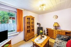 Ein gemütliches Wohnzimmer mit Fernseher, Holzschrank, Kamin und einer Couch.