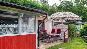 Een rood gebouw met een overdekte patio, een tafel met stoelen en een parasol.