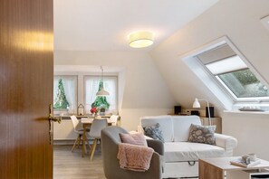 Moderni olohuone, jossa on sohva, ruokailutila ja kattovalokuvio.