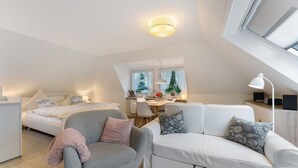 A modern loft apartment with a dining area, a sofa, a chair, and a bed. - Studio Apartment 'Appartement Skagen' with Shared Garden and Wi-Fi (Glücksburg (Ostsee))