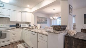 A modern kitchen with white cabinets, a built-in microwave, a coffee maker, and a sink. - 2128 Beachwood (FERNANDINA BEACH)