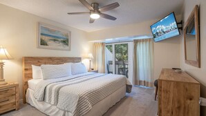 A bedroom with a bed, a ceiling fan, a TV, and a view of the outdoors. - 2128 Beachwood (FERNANDINA BEACH)