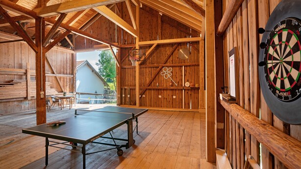 A wooden interior with a ping pong table, dartboard, and a basketball hoop. - Apartment 'Ferienwohnung Marie' with Shared Terrace, Shared Garden and Wi-Fi (Egling)