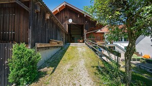 A wooden building with a gravel path leading to a door, surrounded by greenery and a tree. - Apartment 'Ferienwohnung Marie' with Shared Terrace, Shared Garden and Wi-Fi (Egling)