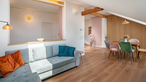 A modern living room with a grey sofa, wooden dining table, and chairs. - Apartment 'Ferienwohnung Marie' with Shared Terrace, Shared Garden and Wi-Fi (Egling)
