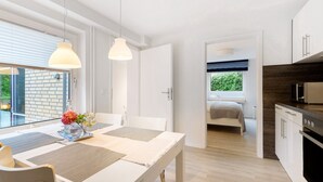 Eine moderne Küche mit weißen Schränken, einem schwarzen Herd und einem Essbereich mit Tisch und Stühlen.