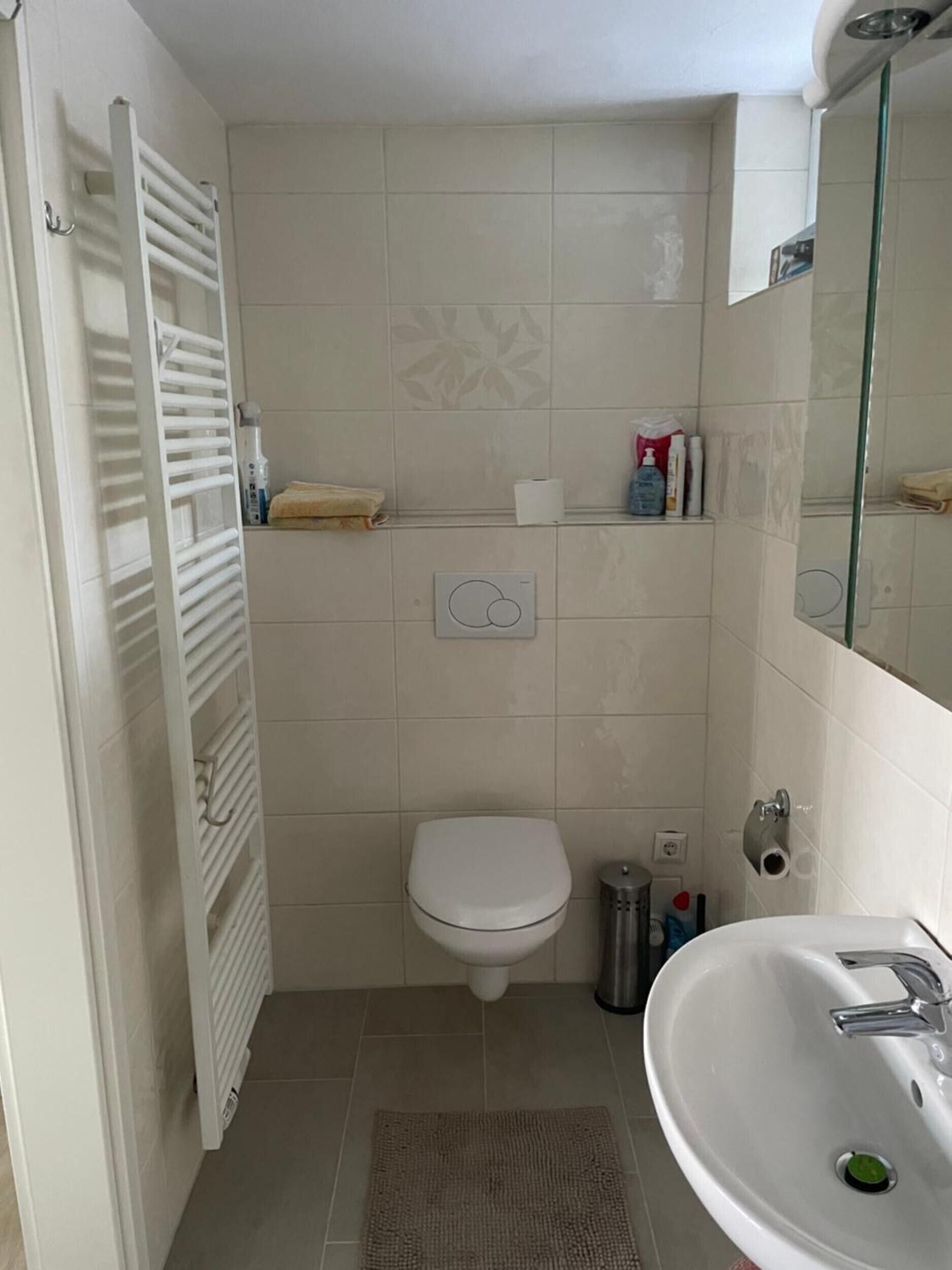 A bathroom with a toilet, a sink, a towel rack, and a shower.