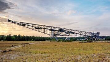 Une grande grue industrielle se dresse dans un champ dégagé, sous un ciel clair.