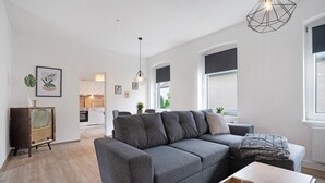Ein modernes Wohnzimmer mit einem grauen Sofa, einem Holztisch und einem Vintage-Radio.