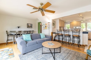 A modern living room with a grey sofa, a round coffee table, and a ceiling fan.