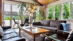 A living room with a sofa, coffee table, and hanging light fixtures. - Holiday Home 'Ferienhaus Christine lake constance north' with Private Terrace and Private Garden (Pfullendorf)