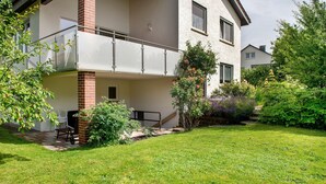 A two-story residential building with a balcony, a brick column, and a well-maintained garden. - Holiday Home 'Ferienhaus Christine lake constance north' with Private Terrace and Private Garden (Pfullendorf)