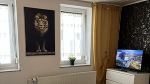 A room with a bed, a table with a book, a TV on a dresser, a window with curtains, and a radiator. - Apartment '2 Ferienwohnung Junghanß' with Wi-Fi (Blankenhain)