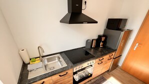 A compact kitchen with a sink, stove, and wooden cabinets. - Apartment '2 Ferienwohnung Junghanß' with Wi-Fi (Blankenhain)