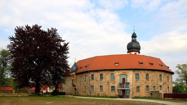 A stone building with a red roof and a central dome, surrounded by a grassy area and trees. - Apartment '2 Ferienwohnung Junghanß' with Wi-Fi (Blankenhain)