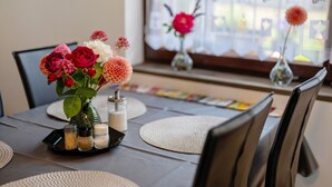 Une table à manger ornée d’un vase de fleurs, de salières et de poivrières, et d’une bougie.